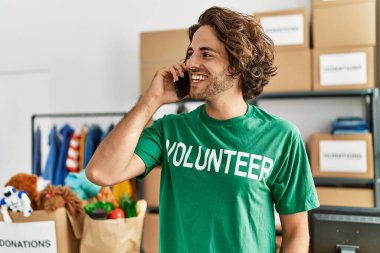 Genç İspanyol gönüllü adam gülümsüyor. Yardım merkezindeki akıllı telefondan konuşuyor..