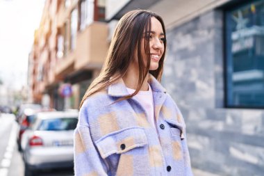 Young beautiful hispanic woman smiling confident looking to the side at street