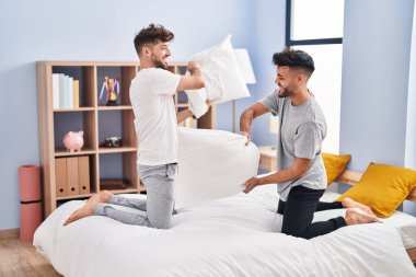 Young couple fighting with pillow on bed at bedrooom