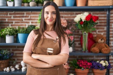 Çiçekçide kollarını kavuşturmuş duran kendine güvenen güzel İspanyol kadın çiçekçi.
