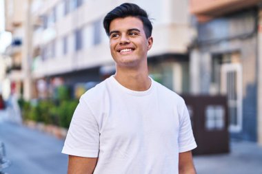 Young hispanic man smiling confident looking to the side at street
