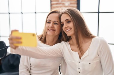 Two women musicians smiling confident make selfie by the smartphone at music studio