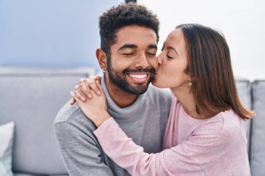 Erkek ve kadın çift evdeki kanepede oturup birbirlerine sarılıyorlar.