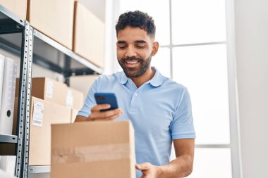 Young hispanic man ecommerce business worker make photo to package at office