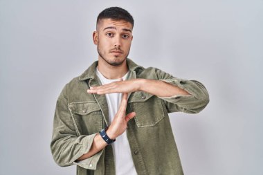 Tecrit edilmiş arka planda duran genç İspanyol adam. Elleriyle hareket ediyor, hayal kırıklığına uğramış ve ciddi bir yüz ifadesi takınıyor. 