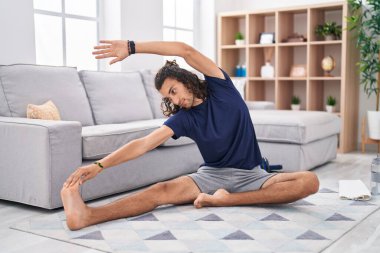 Young hispanic man training yoga at home