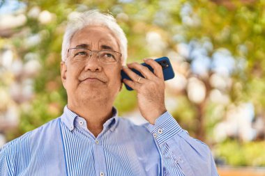 Park 'taki akıllı telefondan sesli mesaj dinleyen kıdemli adam.