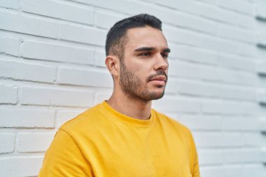 Soyutlanmış beyaz arka planda ciddi bir ifadeyle yan tarafa bakan İspanyol genç adam.