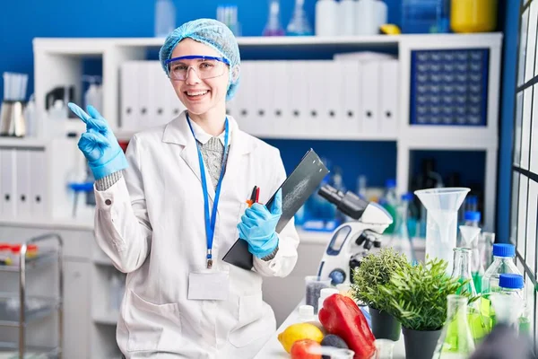 側に手と指を指して幸せな笑顔食品と科学研究所で働く美しい女性 — ストック写真