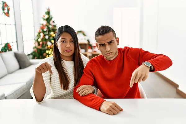 Young Latin Couple Sitting Table Christmas Tree Pointing Looking Sad — Stok fotoğraf