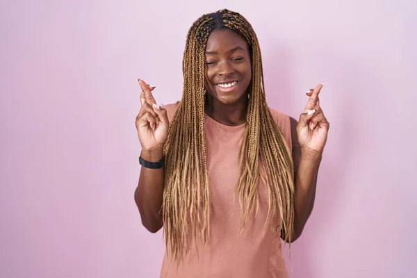 Африканская Американка Плетеными Волосами Стоящая Розовом Фоне Жестом Скрестила Пальцы — стоковое фото