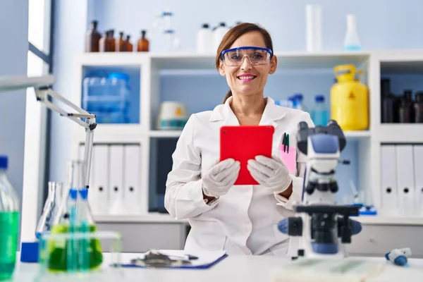中年妇女穿着科学家制服 在实验室使用触摸板 — 图库照片