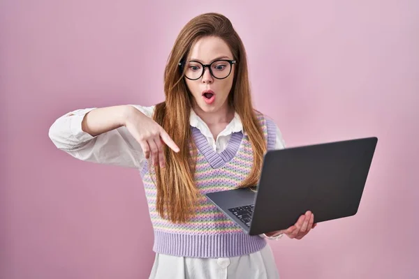 年轻的高加索女人使用电脑笔记本电脑 手指垂下 展示广告 惊讶的脸和张开的嘴 — 图库照片
