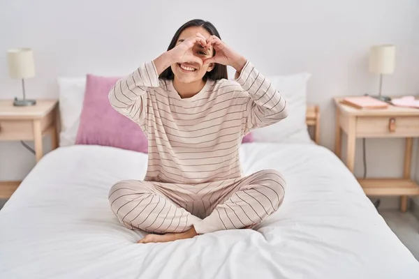 年轻的惊慌失措的女人坐在床上做着心动的姿势 — 图库照片