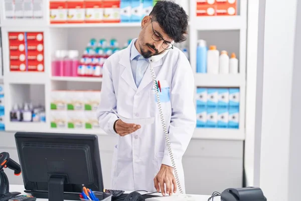 Jovem Hispânico Homem Farmacêutico Falando Por Telefone Segurando Prescrição Farmácia — Fotografia de Stock