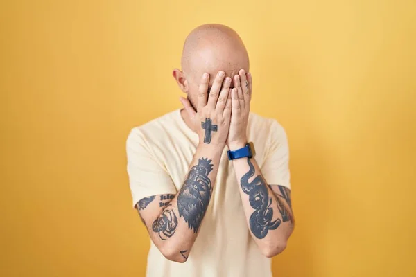 泣きながら手で顔を覆う悲しい表情で黄色の背景に立って入れ墨を持つヒスパニック系の男 うつ病の概念 — ストック写真