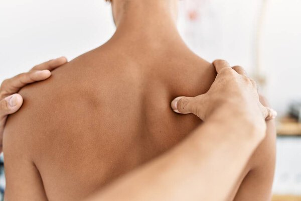 Два испаноязычных мужчины физиотерапевта и пациент, проходящие реабилитацию сеанс массажа обратно в клинике