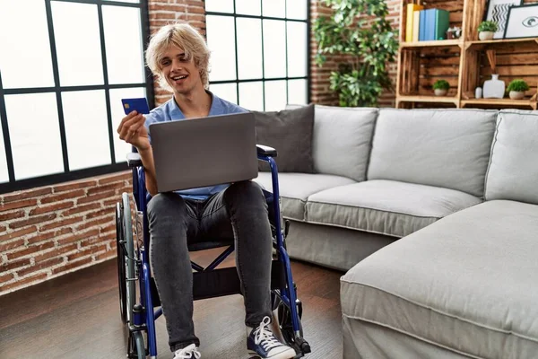 Jovem Loiro Usando Laptop Cartão Crédito Sentado Cadeira Rodas Casa — Fotografia de Stock