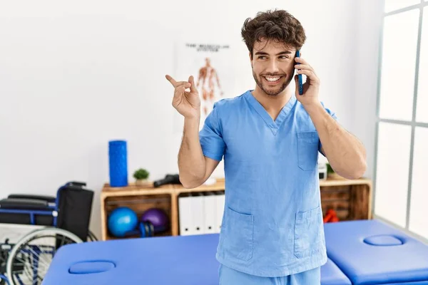 Der Hispanische Physiotherapeut Arbeitet Einer Schmerzklinik Und Telefoniert Glücklich Lächelnd — Stockfoto