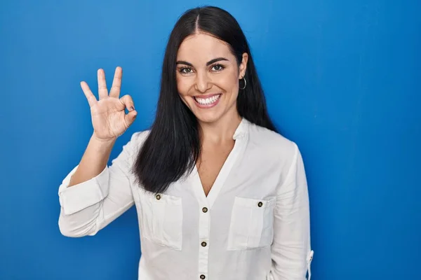 Ung Latinamerikansk Kvinna Står Över Blå Bakgrund Ler Positivt Gör — Stockfoto