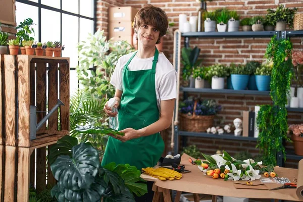 Young blond man florist using difusser working at flower shop