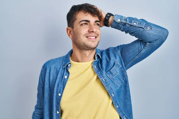 Jovem Hispânico Homem Sobre Fundo Azul Sorrindo Confiante Tocando Cabelo — Fotografia de Stock