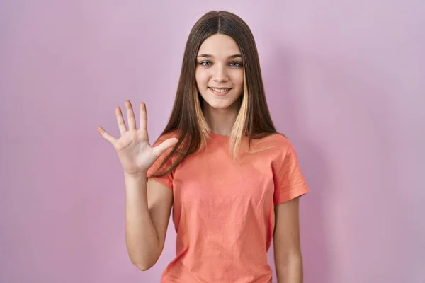 少女站在粉红的背景上 用五号手指指指着 面带微笑 自信而快乐 — 图库照片