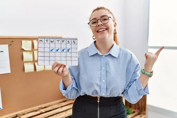 Jonge Roodharige Vrouw Met Reiskalender Kantoor Glimlachend Vrolijk Wijzend Met — Stockfoto
