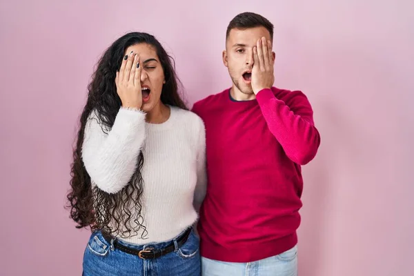 Young Hispanic Couple Standing Pink Background Yawning Tired Covering Half — Stockfoto