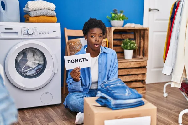 African american woman donating clothes scared and amazed with open mouth for surprise, disbelief face