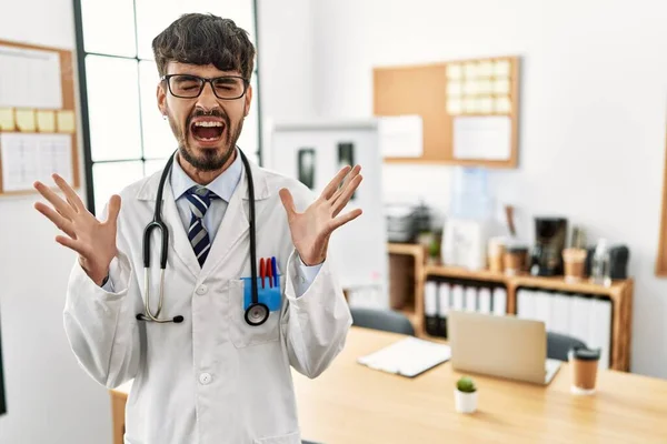 身穿医生制服 头戴听诊器 留着胡子的西班牙裔男子在办公室庆祝疯狂和疯狂的成功 举起双臂 闭上眼睛 兴奋地尖叫着 获奖者概念 — 图库照片