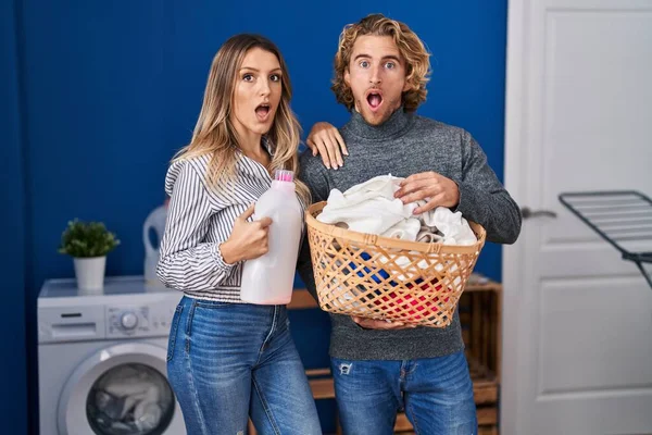 Couple Holding Laundry Basket Detergent Bottle Afraid Shocked Surprise Amazed — Zdjęcie stockowe