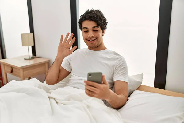 Молодий Іспаномовний Чоловік Має Відеодзвінок Допомогою Смартфона Сидить Ліжку Спальні — стокове фото