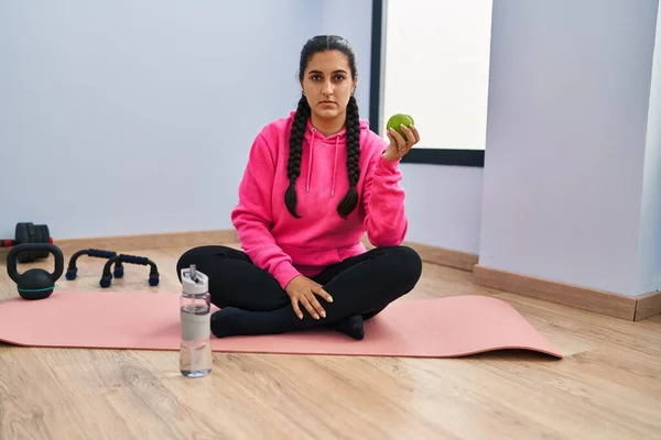 Young Hispanic Woman Sitting Yoga Mat Eating Apple Thinking Attitude — Stockfoto