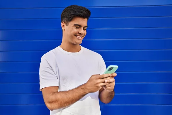 Giovane Uomo Ispanico Sorridente Fiducioso Utilizzando Smartphone Sfondo Blu Isolato — Foto Stock