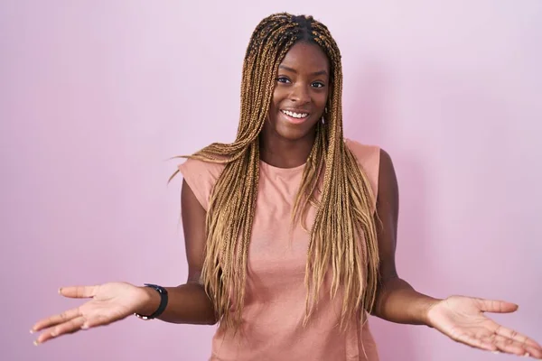 Африканская Американка Плетеными Волосами Стоящая Розовом Фоне Весело Улыбаясь Предлагая — стоковое фото