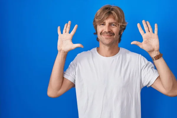 Мужчина Средних Лет Стоит Синем Фоне Показывая Указывая Пальцами Номер — стоковое фото