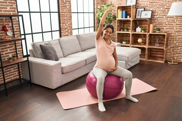 年轻的拉丁裔孕妇在家里用合适的球伸展身体 — 图库照片