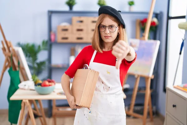 Young Redhead Woman Art Studio Holding Art Case Looking Unhappy — Stock Photo, Image