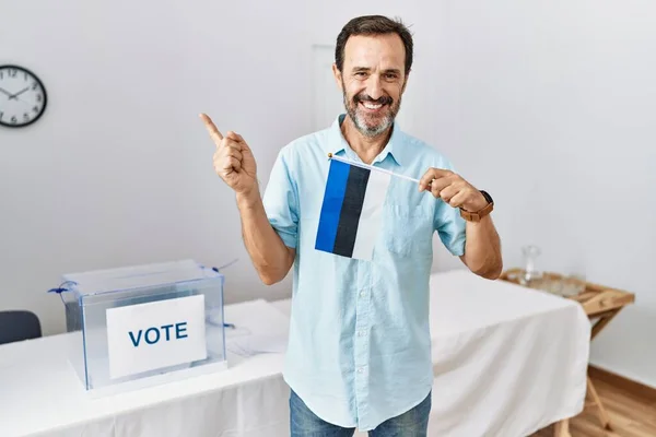 政治選挙で髭を生やした中年男性手と指で側に幸せな指して笑顔Estoniaフラグを保持します — ストック写真