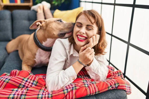 Young caucasian woman smiling confident lying on sofa with dog at home