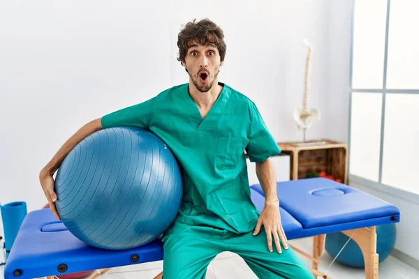 Young Hispanic Physiotherapist Man Holding Pilates Ball Pain Recovery Clinic — Stockfoto