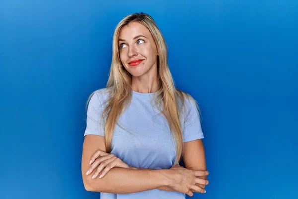 Mooie Blonde Vrouw Dragen Casual Shirt Blauwe Achtergrond Glimlachen Kijken — Stockfoto