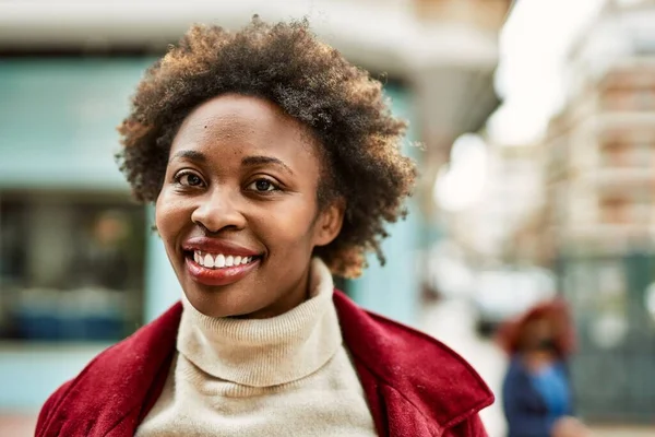 Beautiful business african american woman with afro hair smiling happy and confident outdoors at the city