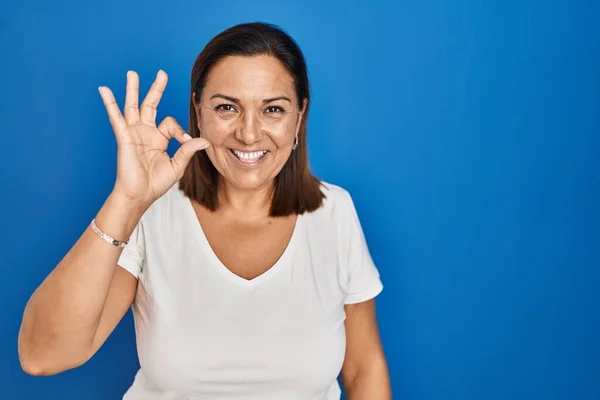 Hispanic Mogen Kvinna Står Över Blå Bakgrund Ler Positivt Gör — Stockfoto