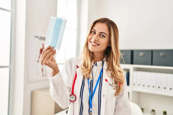 Young Blonde Woman Wearing Doctor Uniform Holding Medical Mask Clinic — Stock Photo, Image