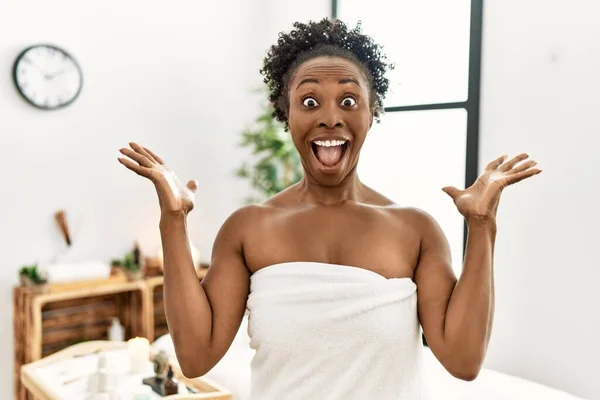 Młoda Afroamerykanka Ubrana Ręcznik Stojąca Centrum Piękności Świętująca Zwycięstwo Szczęśliwym — Zdjęcie stockowe