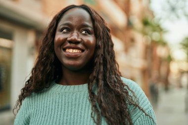 Genç Afrikalı kadın şehirde mutlu gülümsüyor.