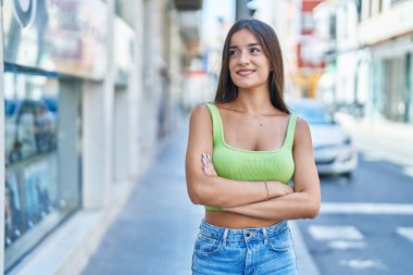 Sokakta kollarını kavuşturmuş genç, güzel İspanyol bir kadın.