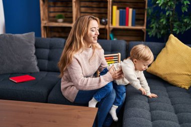 Mother and son hugging each other sitting on sofa at home